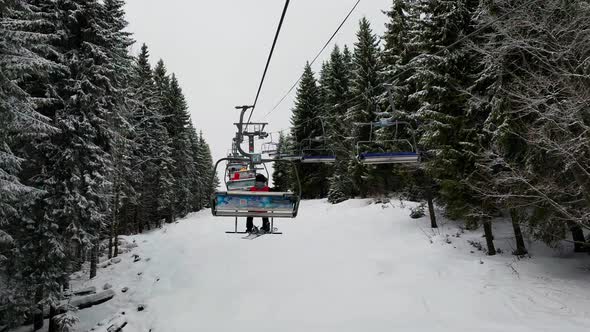 Empty Skilifts Moving On The Ropeway Above Ski Slope In Austrian Alps With People Skiing On The