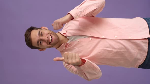 Vertical Studio Portrait of Joyful Young Man Showing Double Thumbs Up and Smiling Looking at Camera