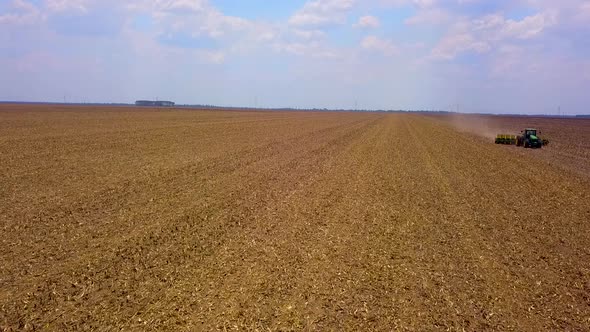 Aerial shot of a tractor plowing a dry field