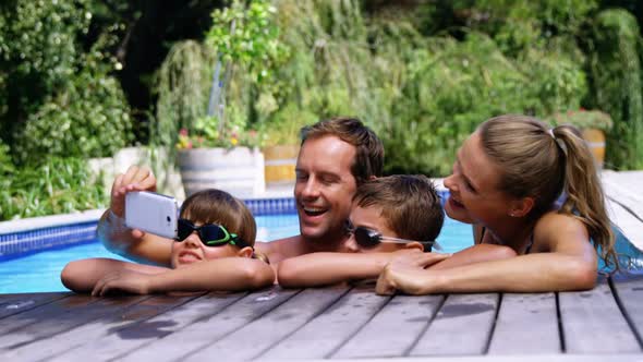 Happy family using mobile phone near poolside