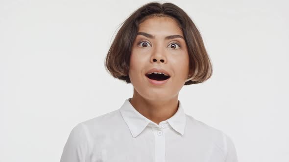 Young Beautiful East Asian Female in Shirt Suprisingly Smiling Twice on White Background in