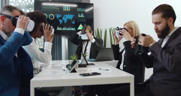 Multiethnic Office Coworkers Putting on Virtual Reality Headset During Joint Work in Boardroom