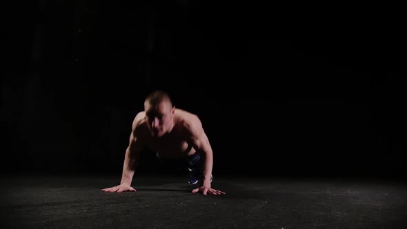 A Young Sports Man Doing Push Ups in Black Studio