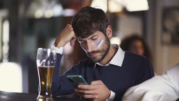 Football Fan Sits in a Bar During a Football Match Drinks Beer and Using Their Smartphone Man Makes