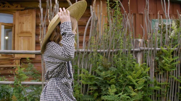 Curly Girl in Hat Walking on Rural Street in Summer Village. Young Teenager Girl Walking on Rustic