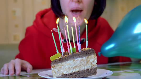 Happy Female Blows Out Candles on a Birthday Piece of Cake