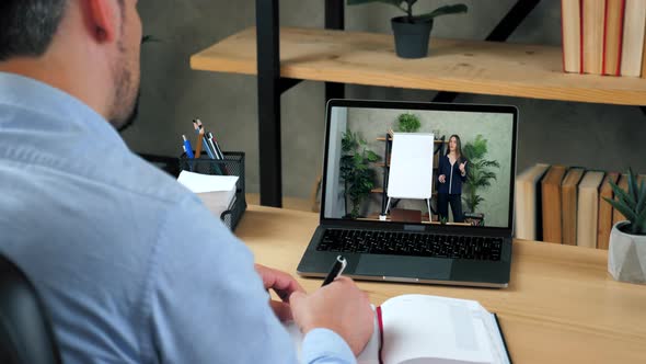 Man in Office Study Online Video Call Laptop Writes in Notebook Listen Teacher