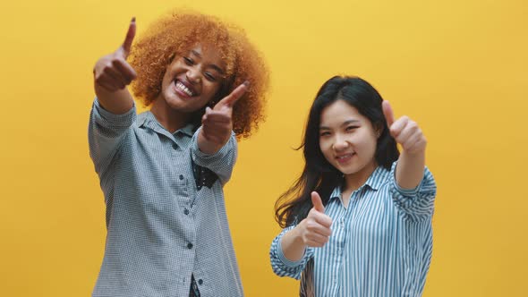 Two Young Girls Showing Thumbs Up. African American Black and Asian Colleagues 