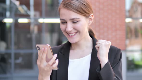 Outdoor Young Businesswoman Excited for Success on Smartphone
