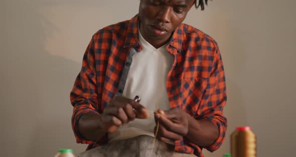 Focused african american craftsman wearing apron working precisely in leather workshop