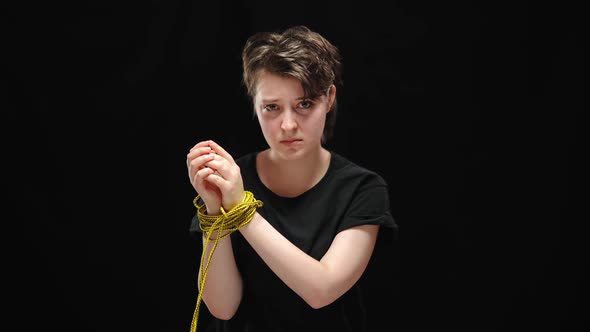 Portrait of Discriminated Young Woman Hands Tied with Rope Looking at Camera with Sad Facial