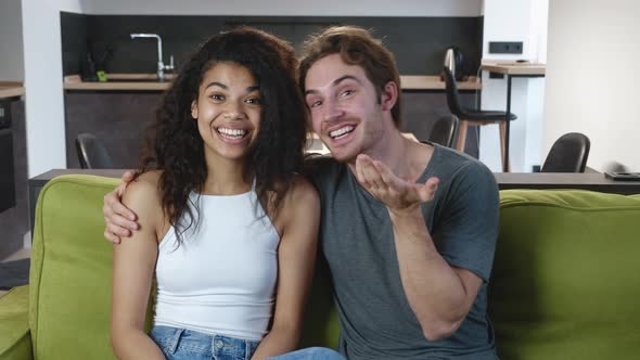 Happy Young Interracial Couple Making Video Call To Announce Their Marriage at Home. Smiling Young
