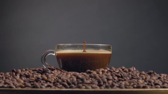 Fragrant Coffee Drops Falling in Espresso Cup Close Up