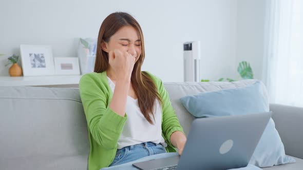 Asian excited young woman winner feeling happy after looks at laptop.