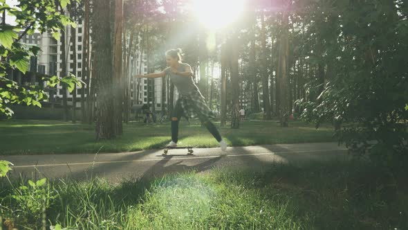 Girl learning to skating on skateboard in park at sunset. Millennial female skateboarding