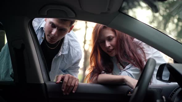 Shooting From Car of Positive Young Couple Talking Looking Inside