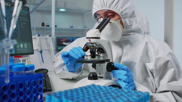 Scientist Wearing Ppe Suit Looking at Samples Under Microscope