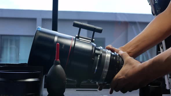 Human hands are rotating the focusing system of the big movie camera zoom lens.