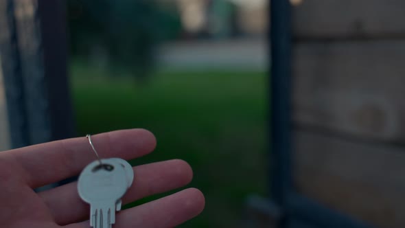 Hand of Woman Holds Keys Walking in Yard to Luxury House