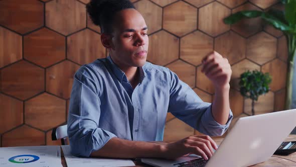 Young Professional African American Man Working with Laptop Sits at Office Table