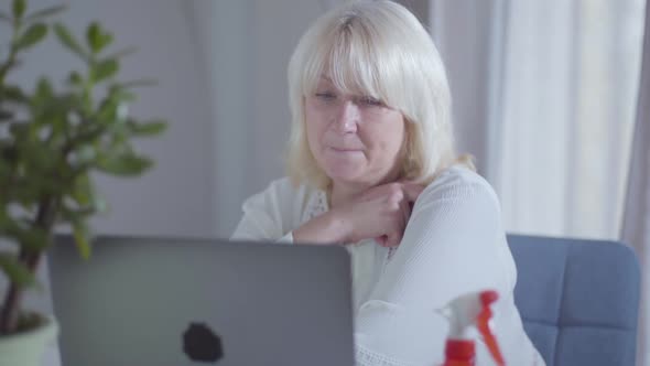 Senior Caucasian Woman Watching Movie on Laptop Screen and Smiling