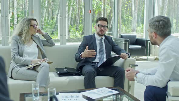 Businessman with Clipboard Discussing Work with Colleagues