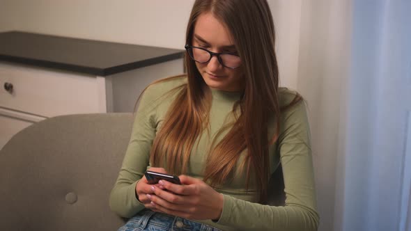 Portrait of Bored Attractive Young Woman in Glasses Yawning While Use Phone for Online Shopping