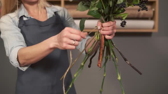 Side View of a Flower Shop Assistant Tying a Bunch of Flowers Holding Them in Hands with the Ribbon