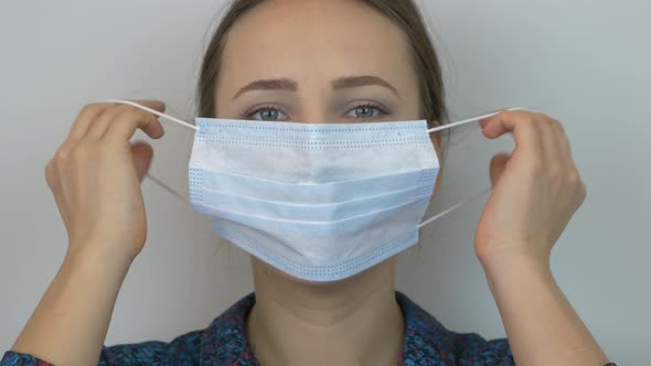 Woman takes off protective medical blue mask and hard breathing, close up. Pandemic concept