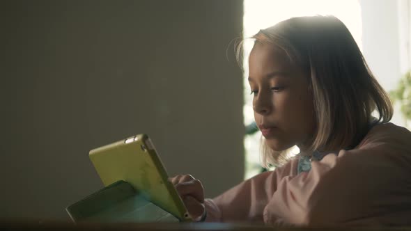 Cute Kid Girl Using Tablet Computer, Young Teenage Child Doing Homework on Digital Tablet 