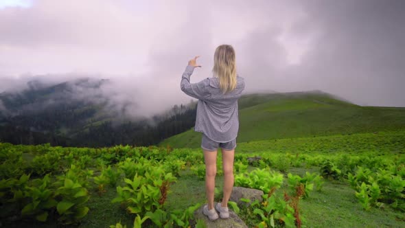 Young girl makes her fingers and hands heart in mountains.