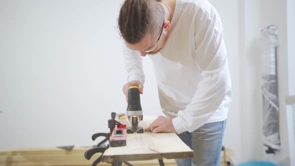 Carpenter in Protective Glasses Cuts Wood with Electric Jigsaw