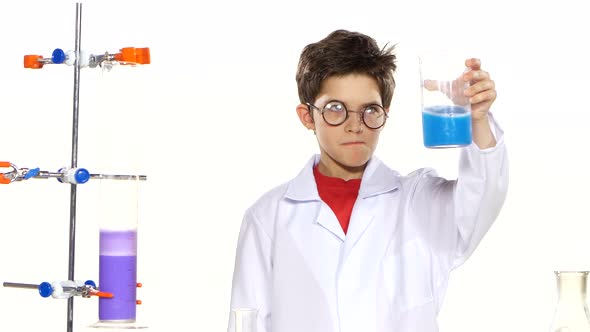 Young Boy Chemist Wearing Uniform, Red Shirt and Round Glasses in Laboratory Making Some Experiment