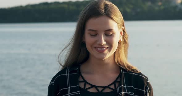 Close Up Portrait of Young Attractive Woman Smiling and Looking at Camera Near Beach at Sunset