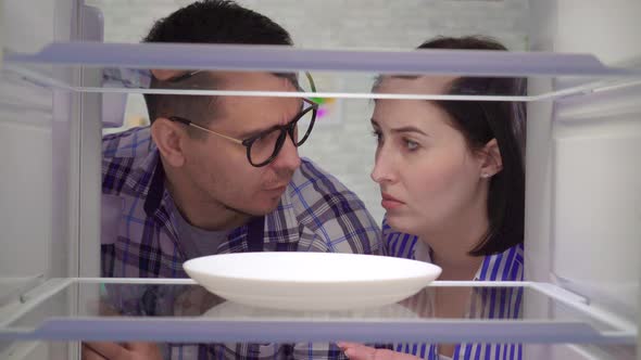 Surprised and Upset a Married Couple Looks Into an Empty Refrigerator