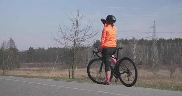 Woman is drinking water and preparing for ride on bike. Woman on bicycle. Woman cycling concept