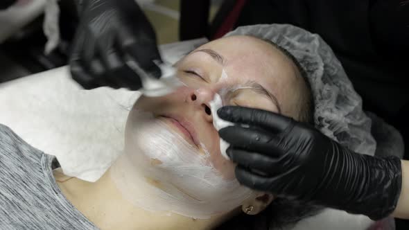 Cosmetologist Clean Clien Woman Face From Moisturizing Mask in Beauty Salon alt