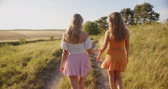 Girls Holding Hands and Laughing Happily While Walking in Nature