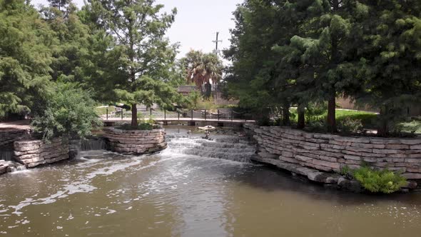 A drone slowly files away from waterfalls on the Riverwalk in San Antonio, Texas.