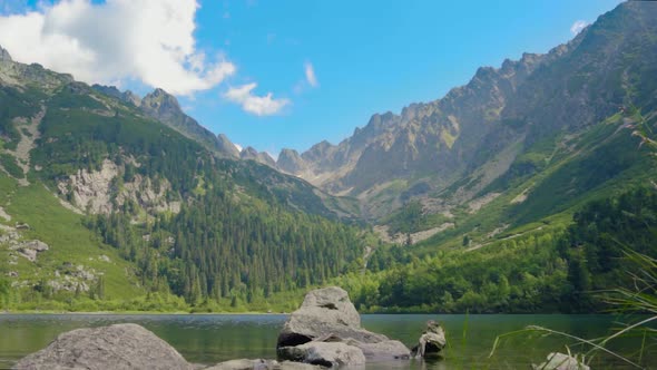 Lovely Mountain Lake with beautiful view over green trees and blue sky mountains