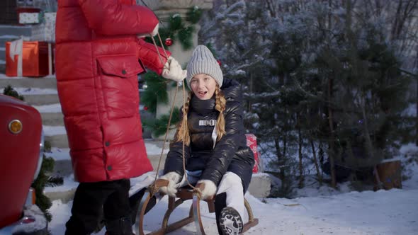 Playful Girl Sledding with Friend on Winter Holidays