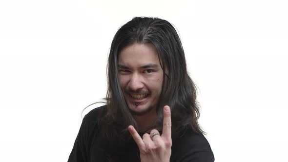 Closeup of Excited Eastasian Rocker with Long Dark Hair and Piercing Showing Heavy Metal Sign with