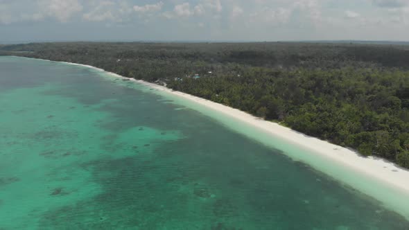 Aerial: flying over tropical beach coral reef turquoise water green forest