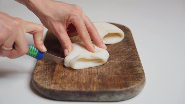Woman Chef Cutting Squid Raw Calamari Into Rings on a Wooden Cutting Board Carefully Close Up Shot