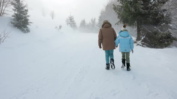 Two Girls Walking Through Snowy Woods