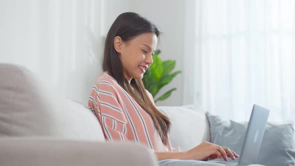 Asian young business woman typing on computer and working from home.