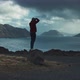 Adventurous photographer standing on a rock taking photos of stunning landscape while it rains - VideoHive Item for Sale