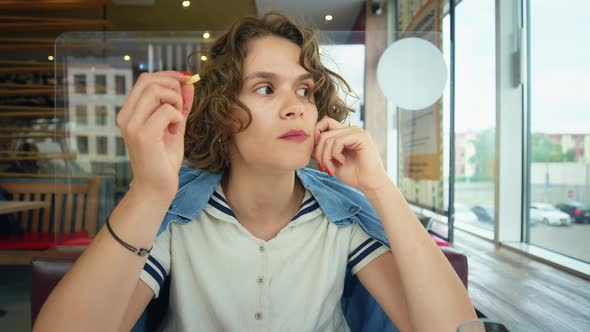 Young Bored Cute Woman Eat French Fries at Cafe