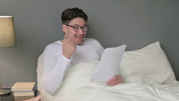 Middle Aged Man with Documents Celebrating Success in Bed 