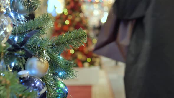 Festive Atmosphere in the Mall. In the Foreground Christmas Fir. Not in Focus People Walk and Buy